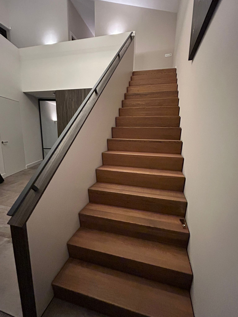 Stalen trapleuning boven op muur langs trap